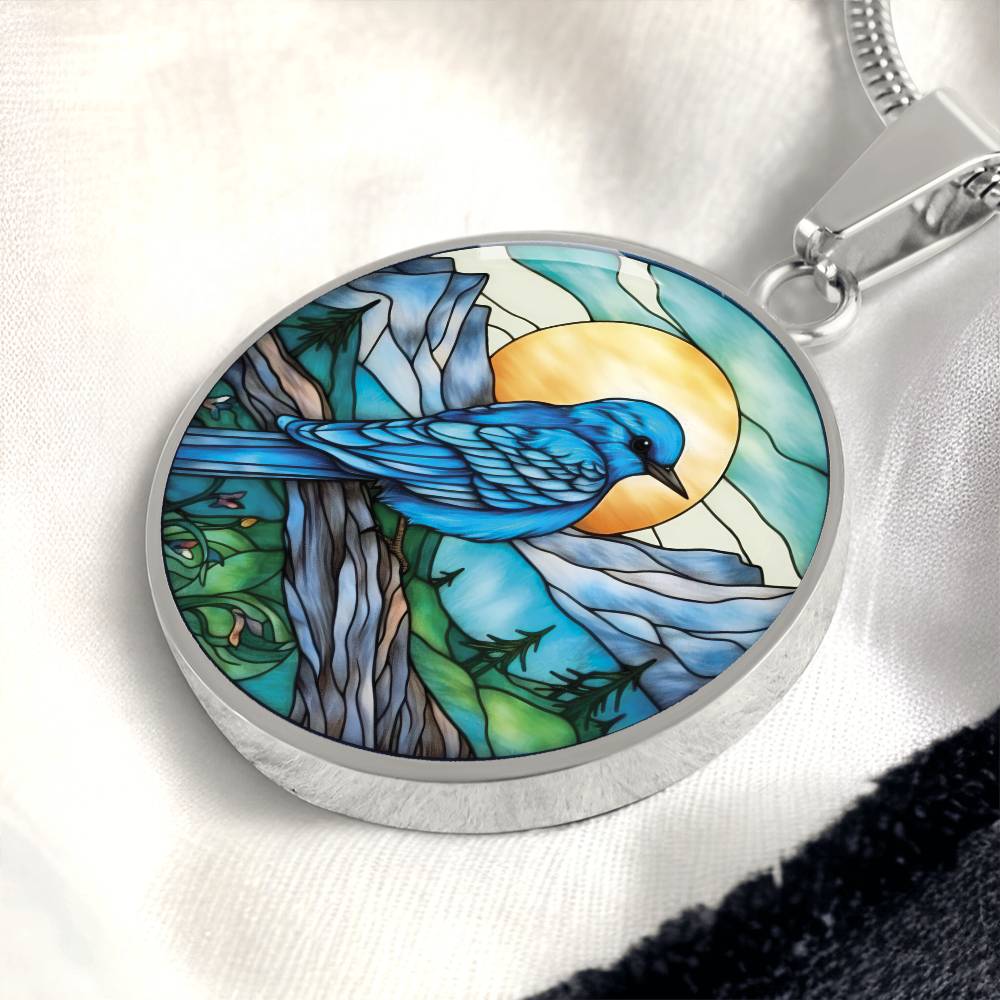 an Elegant silver pendant Blue Bird necklace. Colors blue bird and water, yellow sun, green trees and grass, brown branch, blue and white sky/ mountains. This jewelry offers personalization with an engraving option for a name.