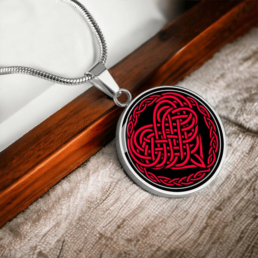Elegant silver pendant featuring a vivid red Heart Celtic Necklace set against a Black & silver backdrop. This jewelry offers personalization with an engraving option for a name.