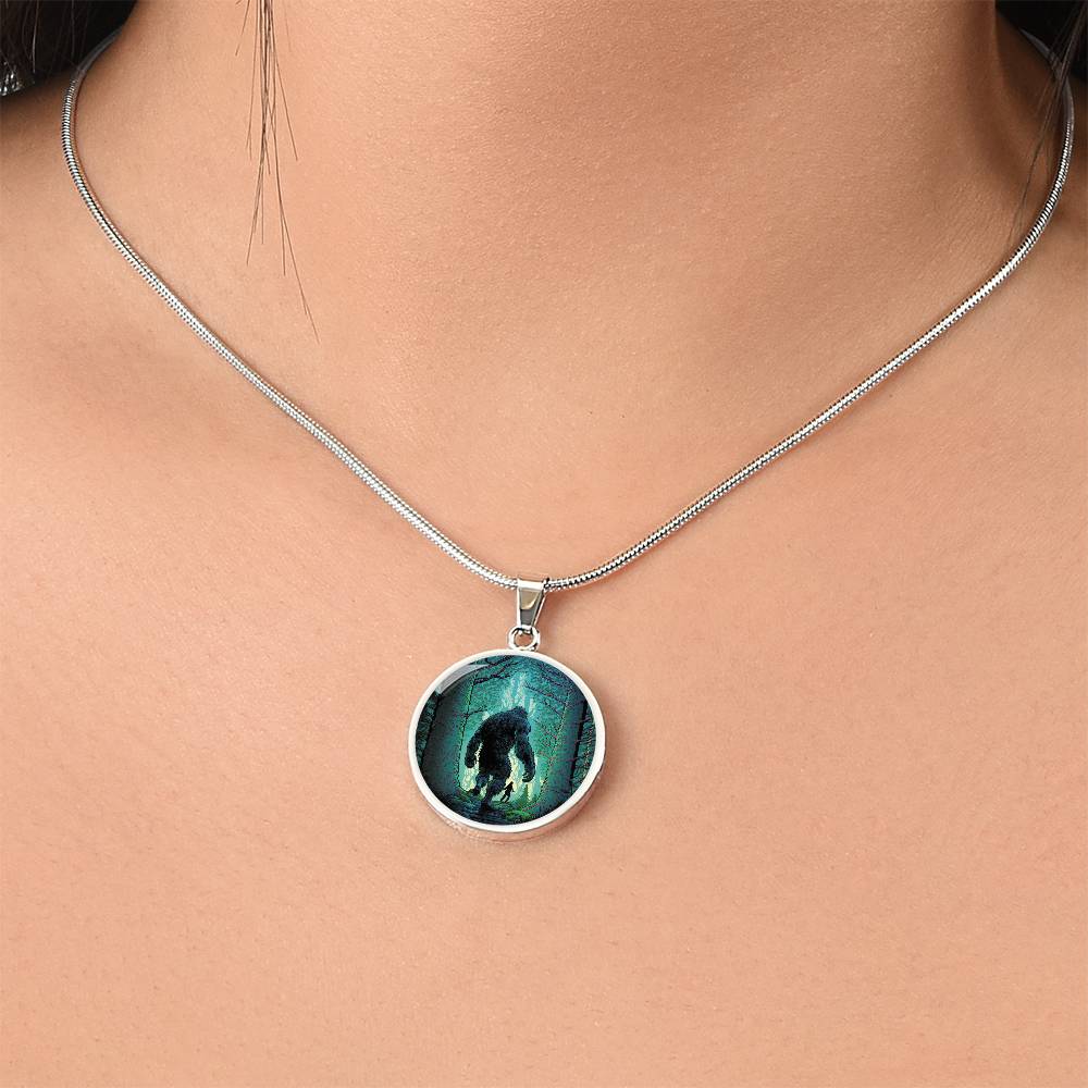 Woman wearing an Elegant silver pendant Bigfoot Necklace. Colors are Green, Brown, Black, Blue and White. This jewelry offers personalization with an engraving option for a name.
