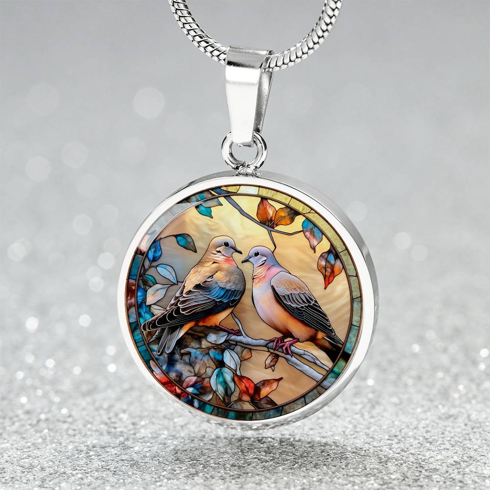 Elegant silver pendant necklace featuring two turtle doves, set against a subtle tan backdrop. This jewelry offers personalization with an engraving option for a name.