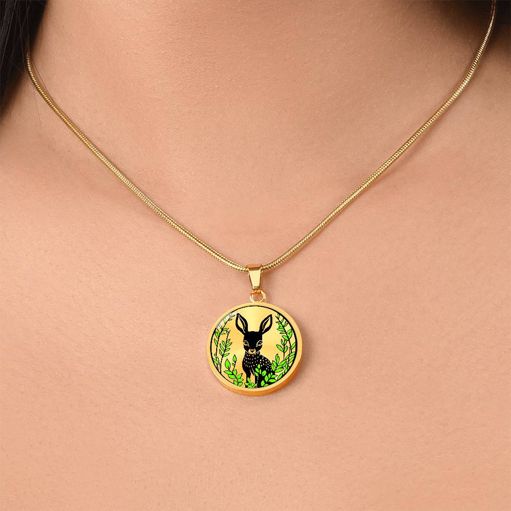 Woman wearing An Elegant gold pendant Deer Necklace. All in gold and black with green leaves. This jewelry offers personalization with an engraving option for a name.