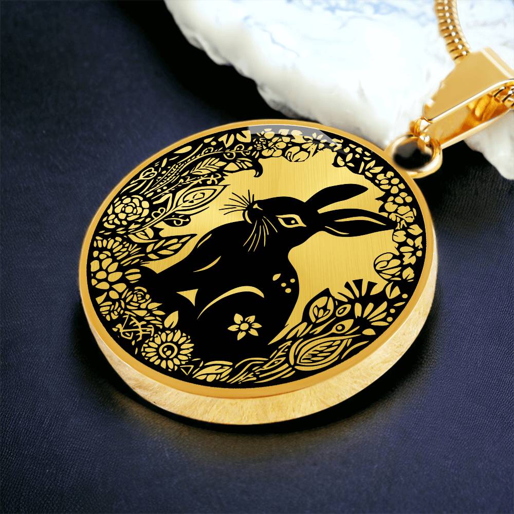 an Elegant gold pendant Easter Bunny necklace featuring a bunny with leaves and flowers all in gold with a black background. This jewelry offers personalization with an engraving option for a name.