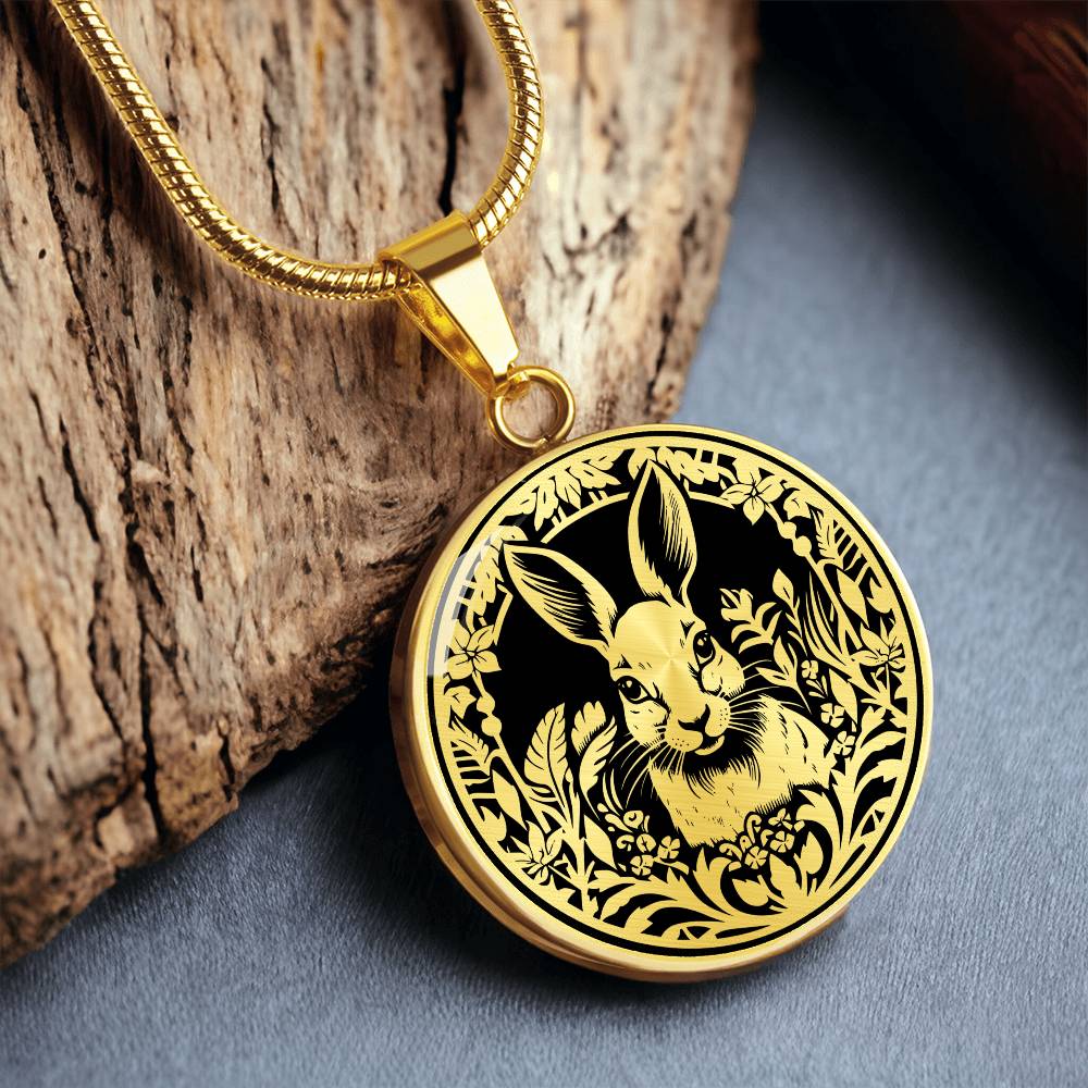 Elegant gold pendant featuring a Rabbit silhouette, The rabbit is hiding in the grass, set against a black backdrop. This necklace offers personalization with an engraving option for a name.