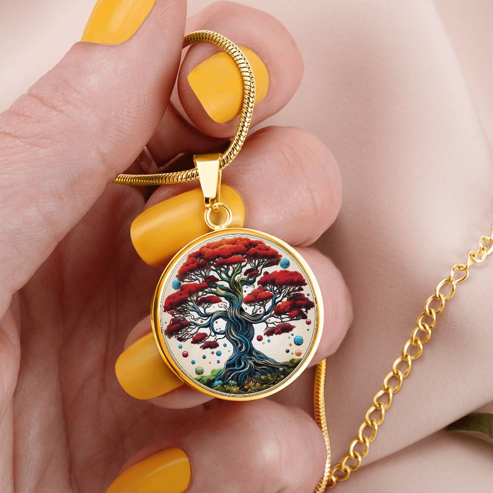 Woman holding an Elegant gold pendant tree of life necklace featuring red leaves, colorful round candy and green grass set against a white backdrop. This jewelry offers personalization with an engraving option for a name.