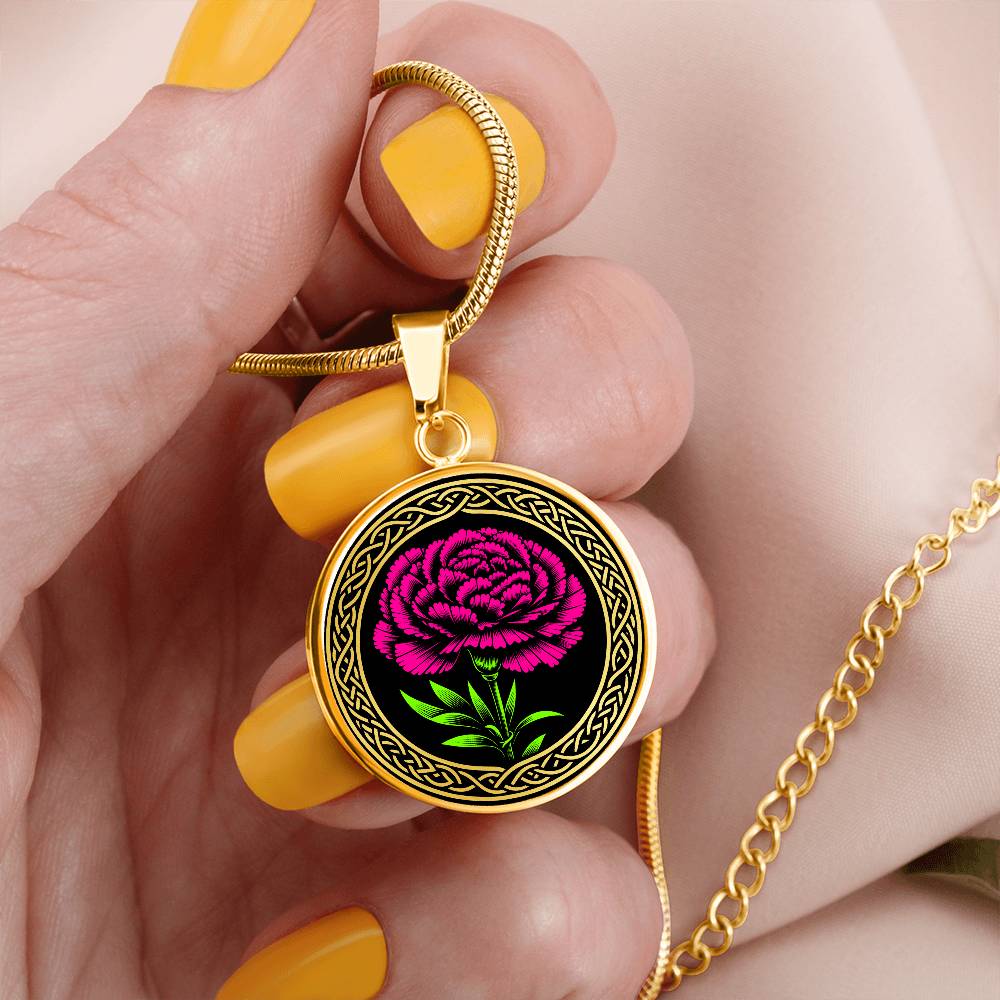 Woman holding an Elegant January Gold pendant Celtic Birth Flower Carnation Necklace. Featuring a vivid pink flower with green leaves, set against a gold & black backdrop. This jewelry offers personalization with an engraving option for a name.