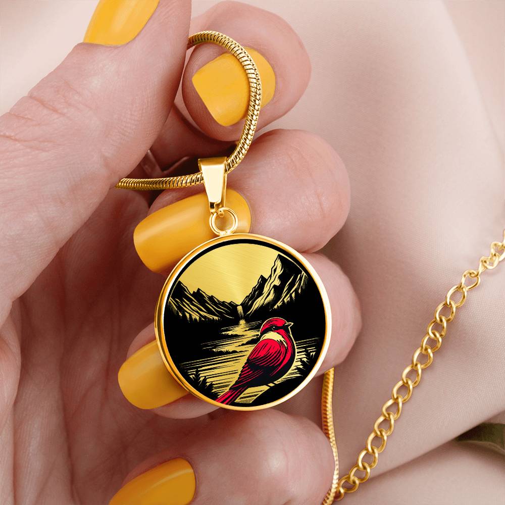 Woman holding an elegant gold pendant Red Cardinal Necklace. The colors are gold, red and black. This jewelry offers personalization with an engraving option for a name.