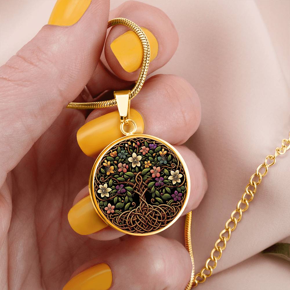 Woman holding an elegant gold pendant Honeysuckle Celtic Tree of Life Necklace. The Colors are yellow, white, pink, purple, green, brown and black. This jewelry offers personalization with an engraving option for a name.