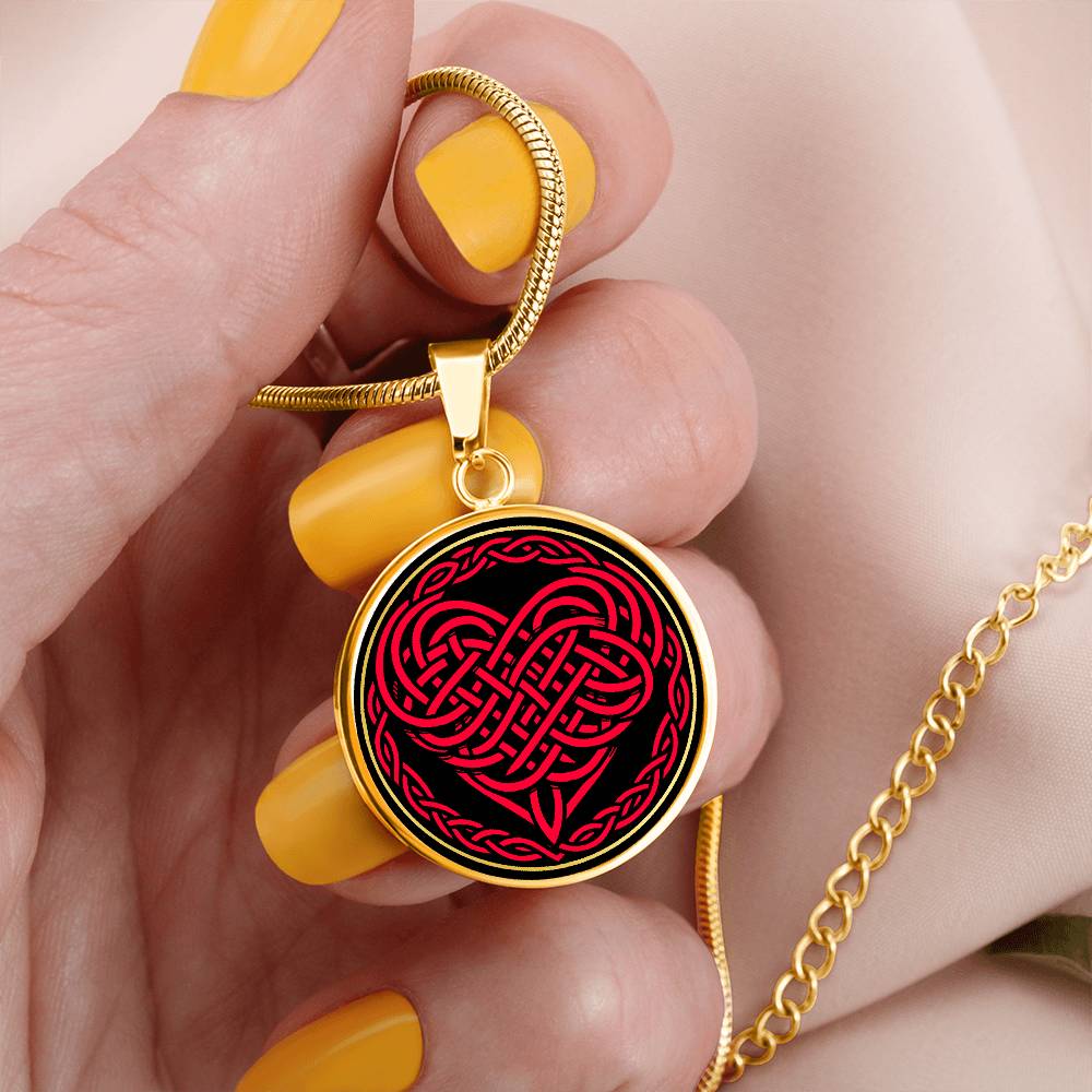 Woman holding an Elegant gold pendant featuring a vivid red Heart Celtic Necklace set against a Black & Gold backdrop. This jewelry offers personalization with an engraving option for a name.