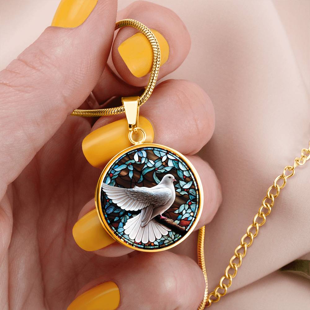 Woman holding an Elegant gold pendant Dove Bird Necklace. featuring a white dove, green, blue, red colored border, leaves, berries with a brown background. This jewelry offers personalization with an engraving option for a name.