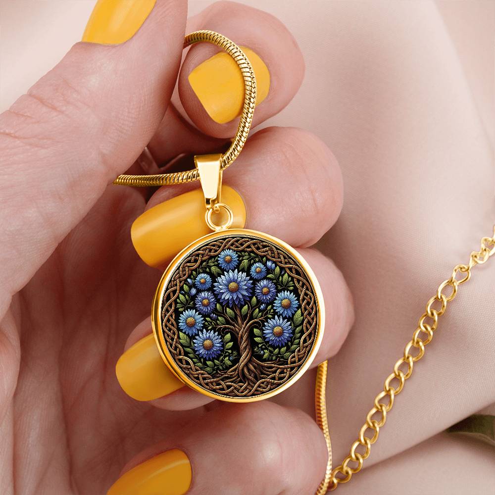 Woman holding an elegant gold pendant Aster Celtic Tree of Life Necklace. The Colors are blue, green, brown and black. This jewelry offers personalization with an engraving option for a name.