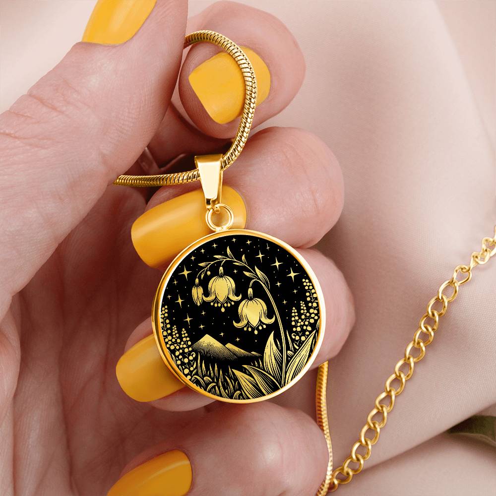 Woman holding An Elegant gold pendant Lily Of The Valley Necklace featuring Mountains, Stars, Grass, Lily Of The Valleys all in black and gold. This jewelry offers personalization with an engraving option for a name.