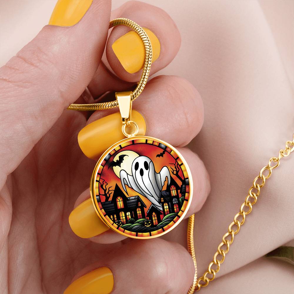 Woman holding an elegant gold pendant Halloween Ghost Necklace. The colors are white, black, yellow, orange and green. This jewelry offers personalization with an engraving option for a name.