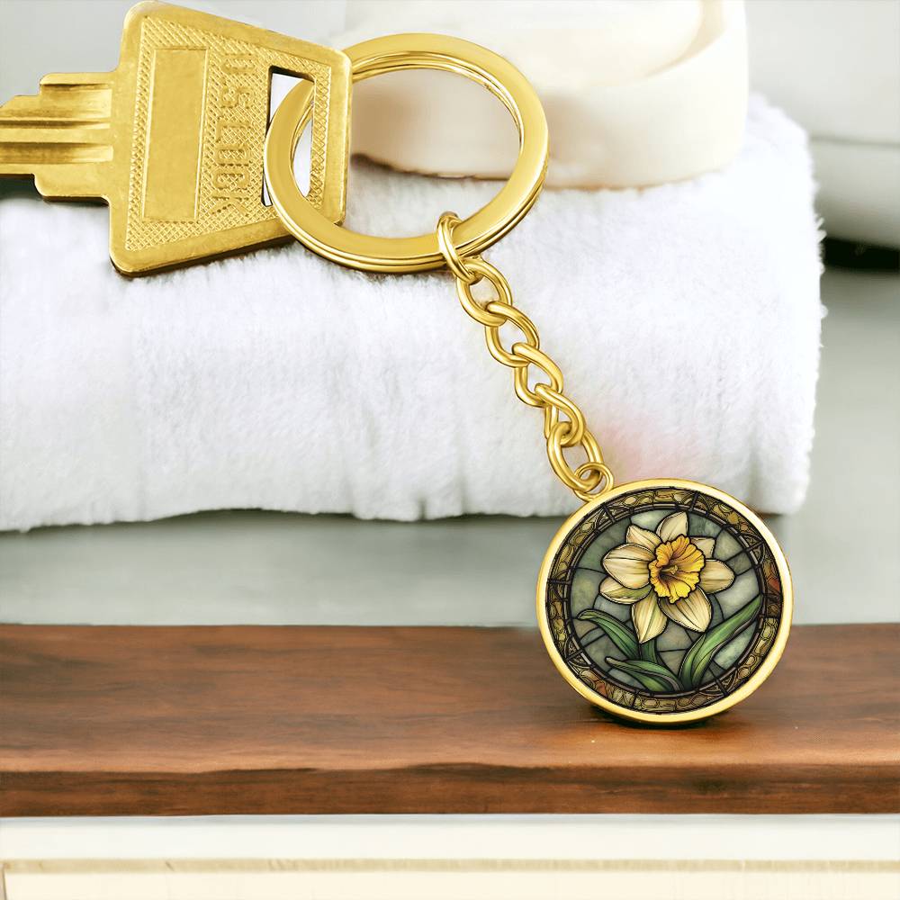 An Elegant Gold pendant Daffodil Necklace, March's birth month flower. Colors, Yellow flower, Green Grass, Brown Border, Dark Green background. This jewelry offers personalization with an engraving option for a name.