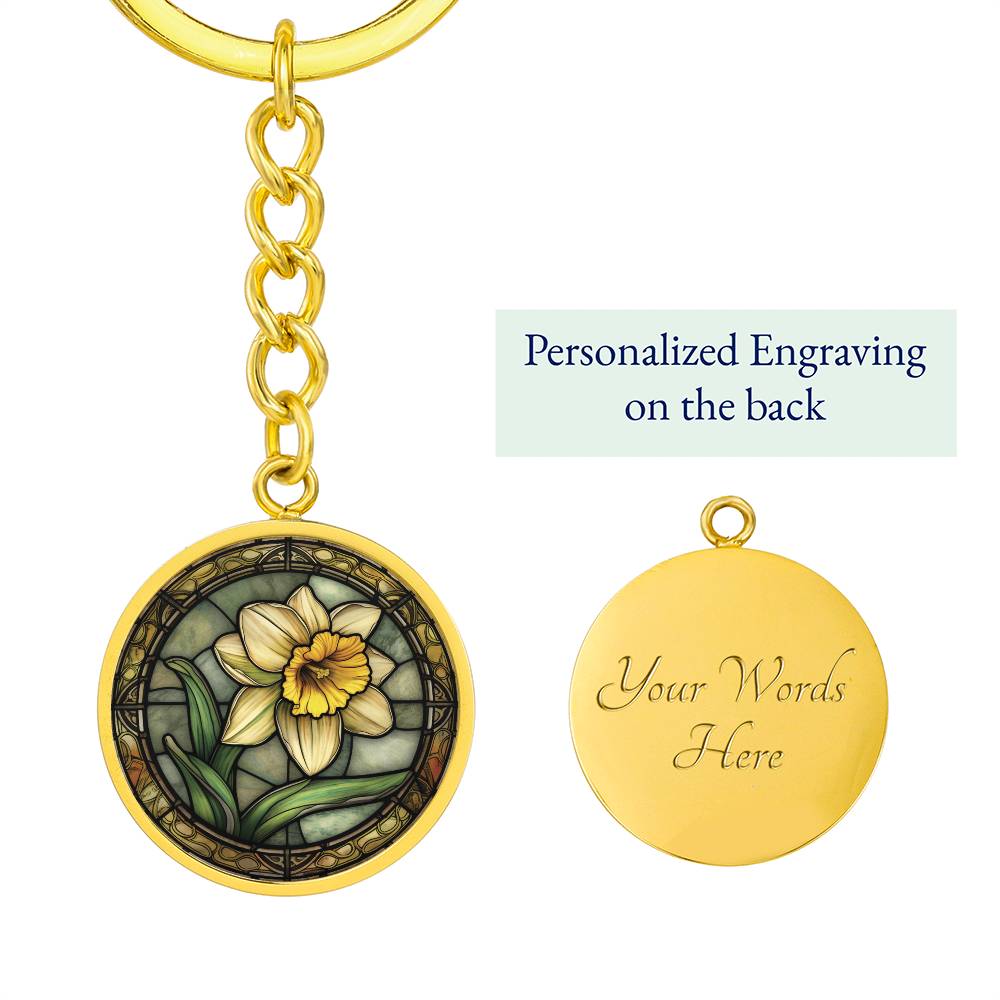 An Elegant Gold pendant Daffodil Necklace, March's birth month flower. Colors, Yellow flower, Green Grass, Brown Border, Dark Green background. This jewelry offers personalization with an engraving option for a name.