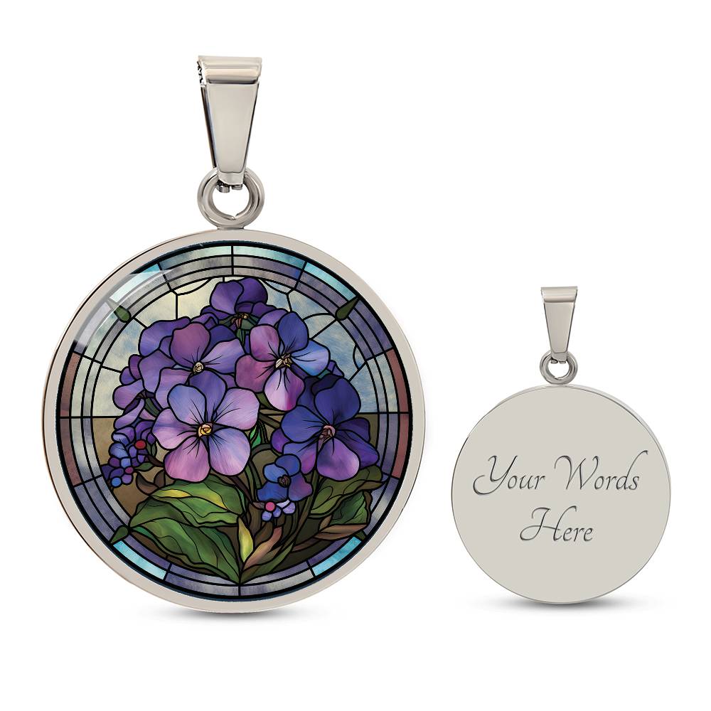 Elegant silver pendant African Violet Birth Flower Necklace. Violet and purple flowers, green grass, blue, purple, brown background. This jewelry offers personalization with an engraving option for a name.