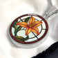 Elegant Silver pendant necklaces features an Orange Tiger Lily, Green Grass, white background with a red and brown frame. This necklace offers personalization with an engraving option for a name.