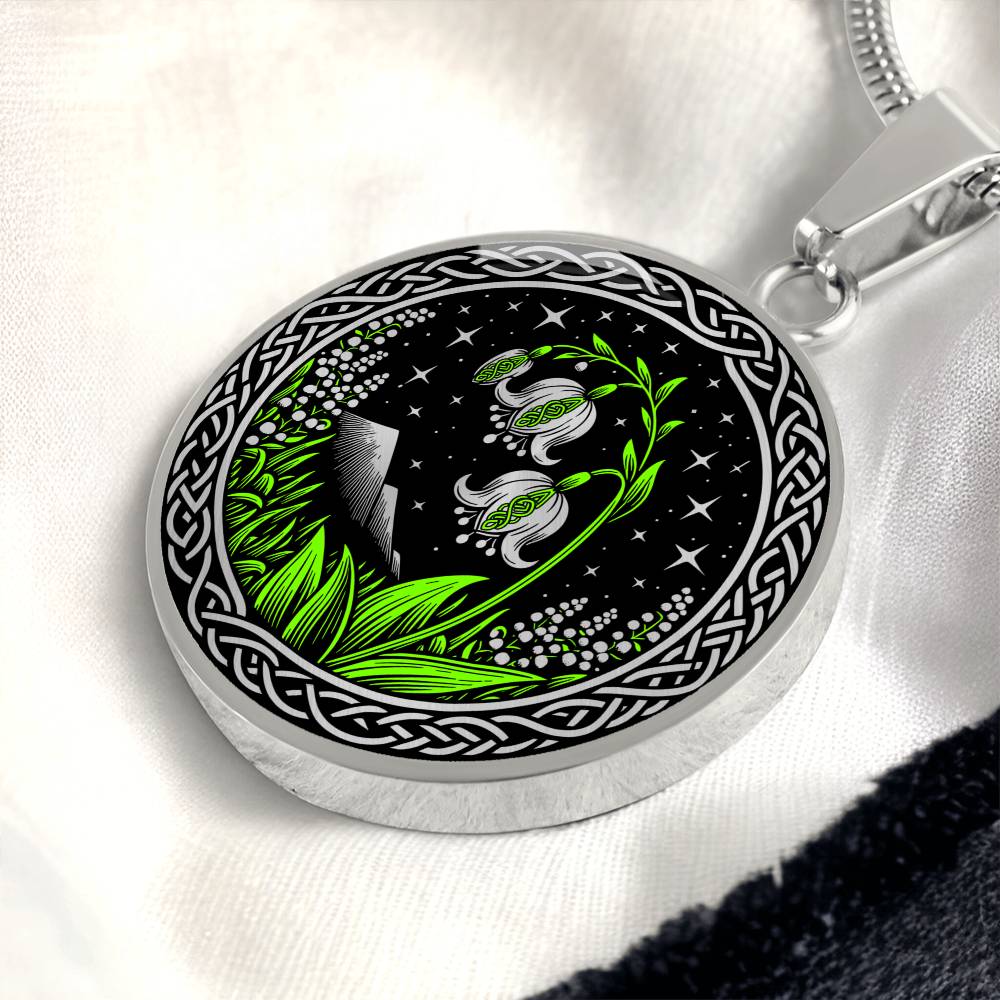 An Elegant silver pendant Celtic Lily Of The Valley Necklace featuring Green Grass, Silver Mountains, Stars,  Lily Of The Valleys, Celtic Knot Frame with a black backdrop. This jewelry offers personalization with an engraving option for a name.