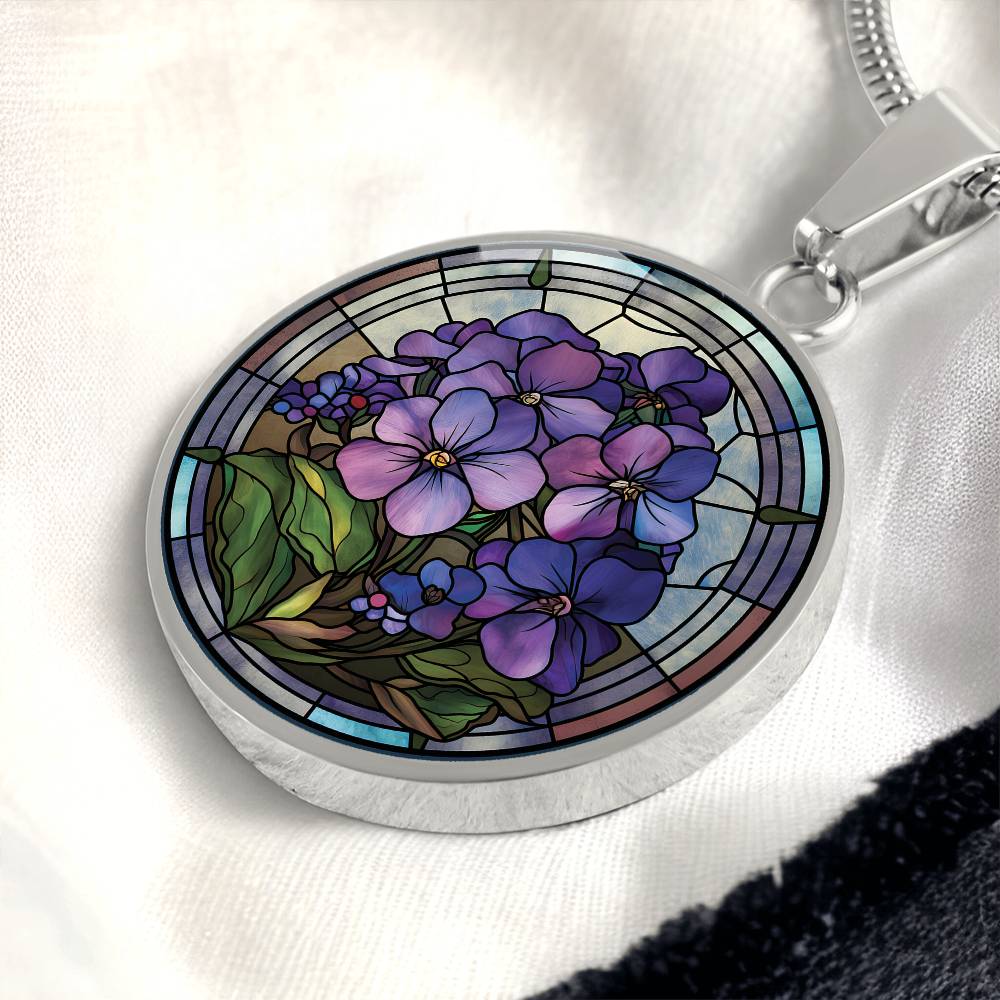 Elegant silver pendant African Violet Birth Flower Necklace. Violet and purple flowers, green grass, blue, purple, brown background. This jewelry offers personalization with an engraving option for a name.