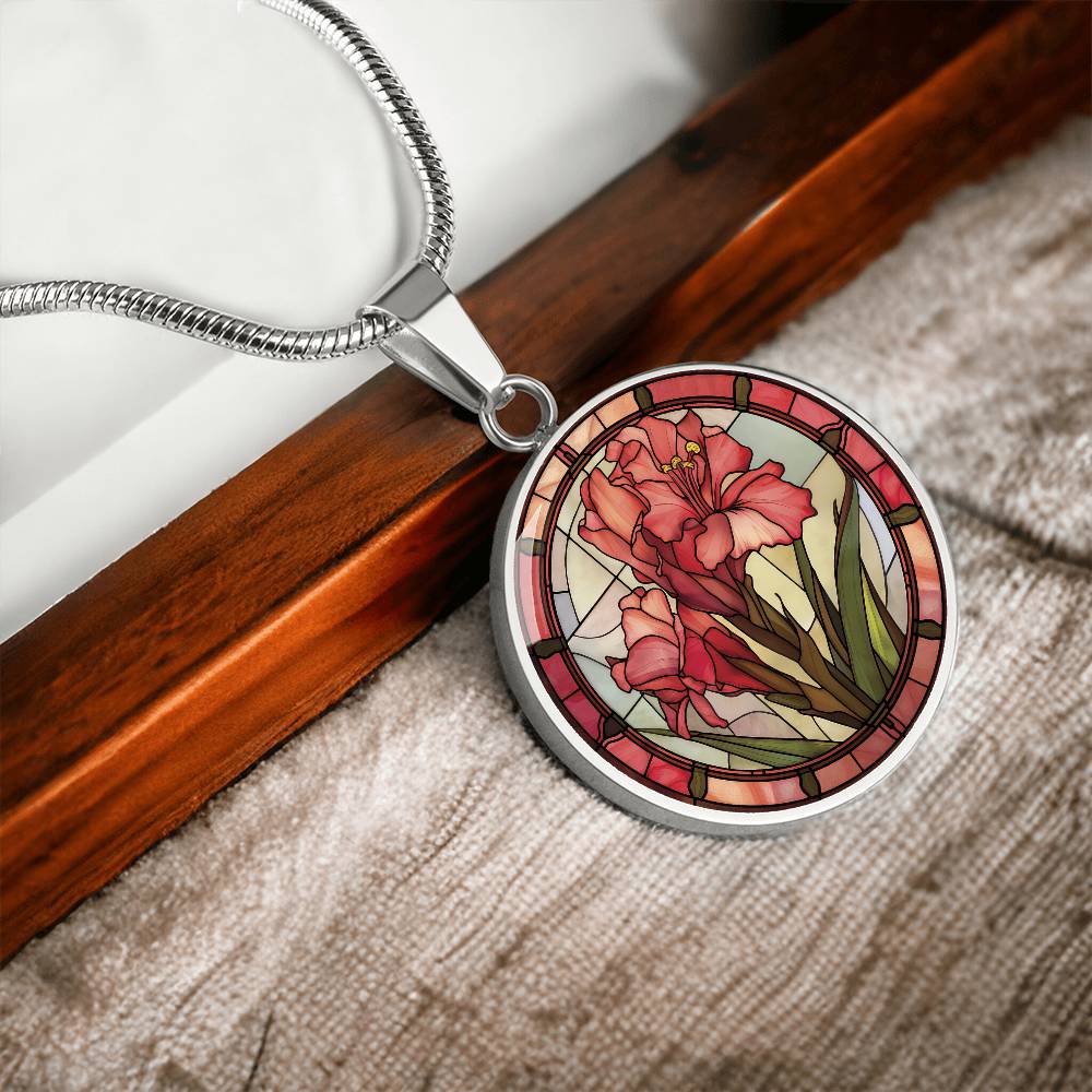 an elegant silver pendant Gladiolus Necklace. The colors are tan/green/blue/purple background, red and pink flowers, green grass, red border. This jewelry offers personalization with an engraving option for a name.