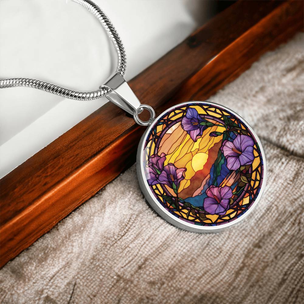 an elegant silver pendant Morning Glory Necklace. The colors are purple flowers, blue/green/purple hills, Brown mountains, Yellow sun and sky. This jewelry offers personalization with an engraving option for a name.