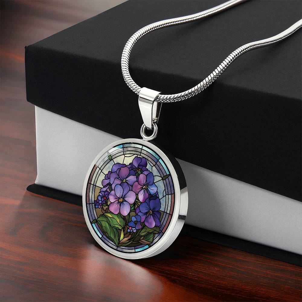 Gift box with an Elegant silver pendant African Violet Birth Flower Necklace. Violet and purple flowers, green grass, blue, purple, brown background. This jewelry offers personalization with an engraving option for a name.