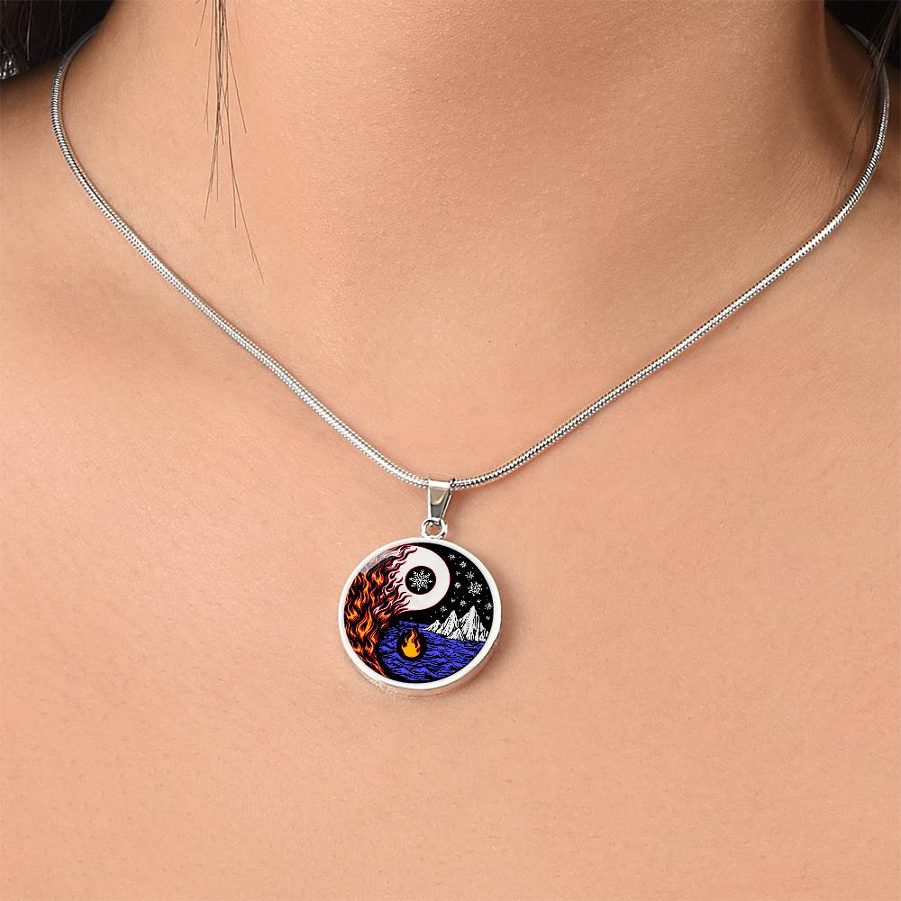 Woman wearing an Elegant silver pendant featuring a vivid Red/Orange Fire, Blue Water, Silver snow flakes and Silver Icebergs. set against a silver & Black backdrop. This jewelry offers personalization with an engraving option for a name.