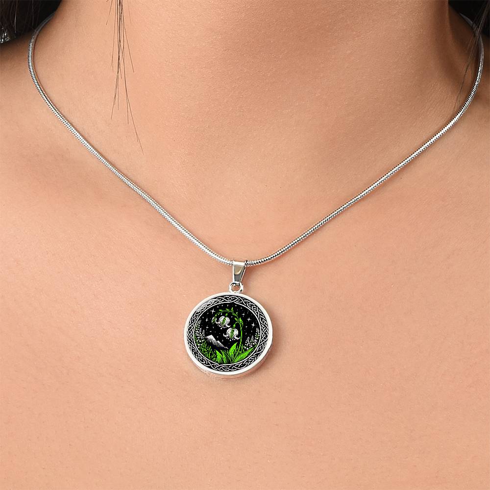 Woman wearing An Elegant silver pendant Celtic Lily Of The Valley Necklace featuring Green Grass, Silver Mountains, Stars,  Lily Of The Valleys, Celtic Knot Frame with a black backdrop. This jewelry offers personalized engraving option for a name.