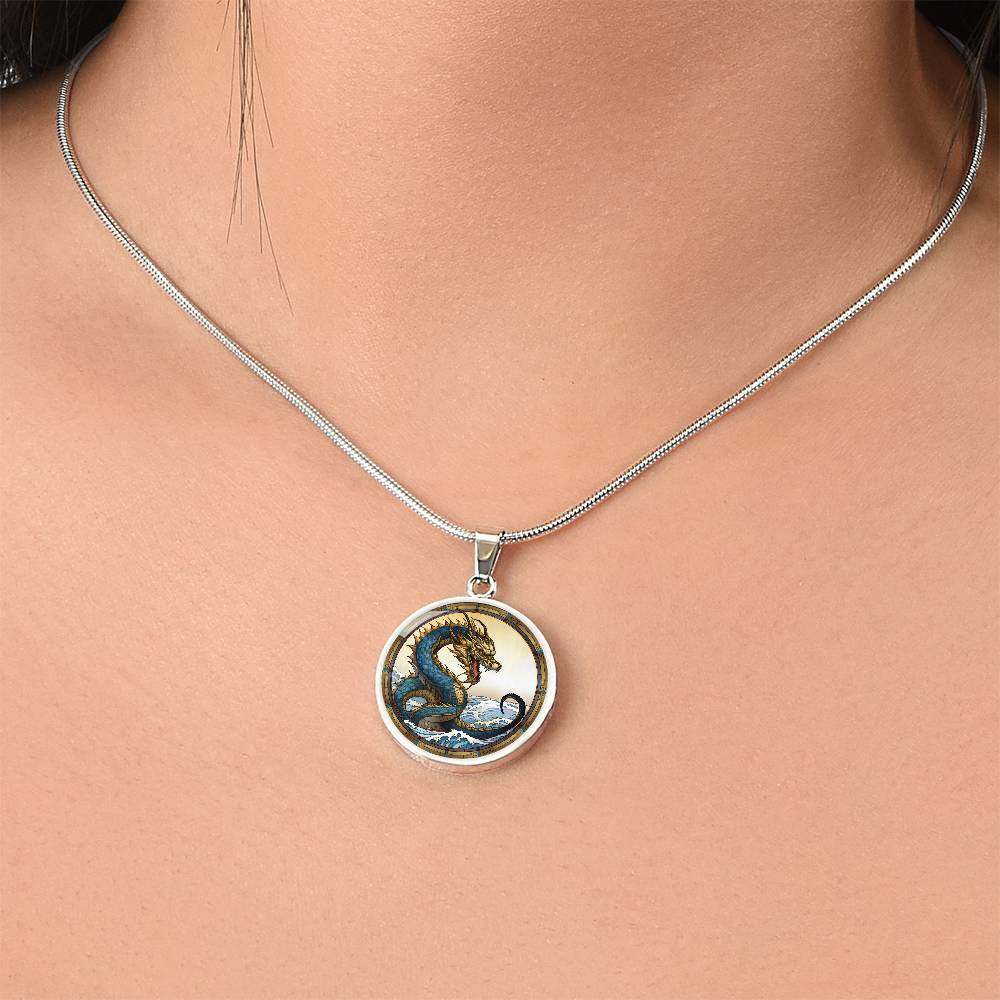 Woman wearing An Elegant silver pendant featuring a Water Dragon Necklace. Blue and yellow Dragon with a blue ocean, tan border and backdrop. This jewelry offers personalization with an engraving option for a name.