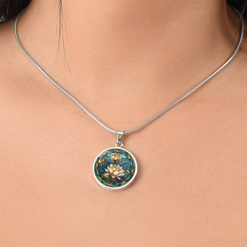 Woman wearing an elegant silver pendant Water Lily Necklace. The colors are Green Leaves, Blue Water and Tan Flowers. This jewelry offers personalization with an engraving option for a name.