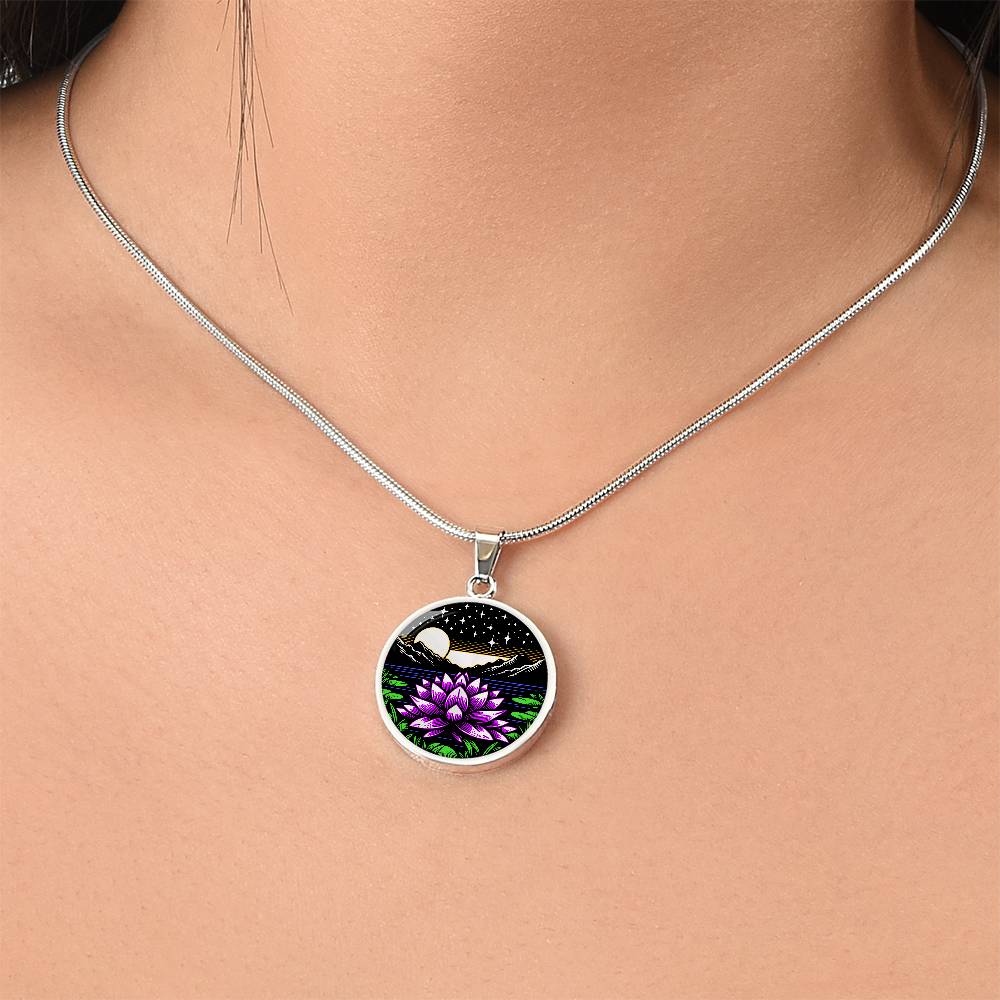 Woman wearing An Elegant silver pendant Water Lily Necklace featuring Mountains, Stars, Yellow outline Sun, Green grass Lily Pads, Blue Water, Pink lily, black and silver Background. This jewelry offers personalization engraving option for a name.