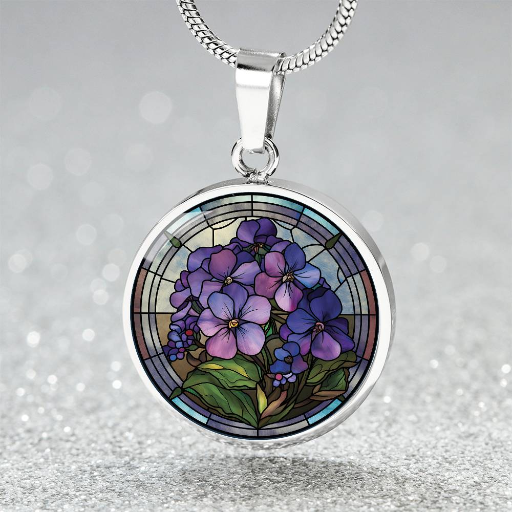 Elegant silver pendant African Violet Birth Flower Necklace. Violet and purple flowers, green grass, blue, purple, brown background. This jewelry offers personalization with an engraving option for a name.