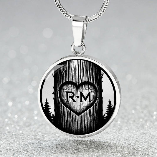 an Elegant Silver pendant Love Heart initial necklace featuring a Heart engraved onto a pine tree, set against a Silver & black backdrop. This jewelry offers personalization with an engraving option for a name.