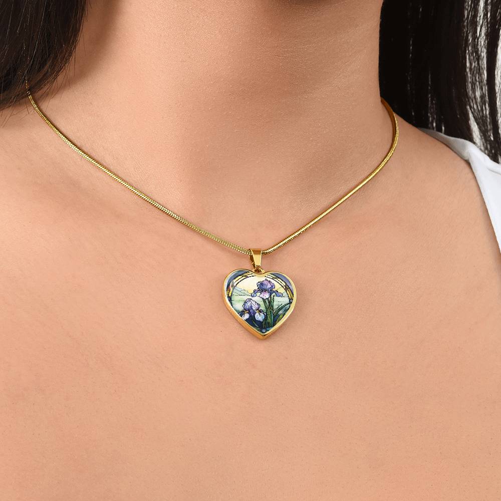 Woman wearing a Gold Heart Pendant Purple Iris flower necklace, With green grass, a Yellow sunset and Green mountains. This necklace offers personalization option for a name.