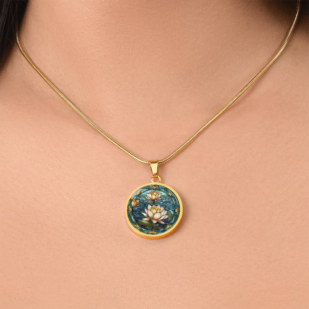 Woman wearing an elegant gold pendant Water Lily Necklace. The colors are Green Leaves, Blue Water and Tan Flowers. This jewelry offers personalization with an engraving option for a name.