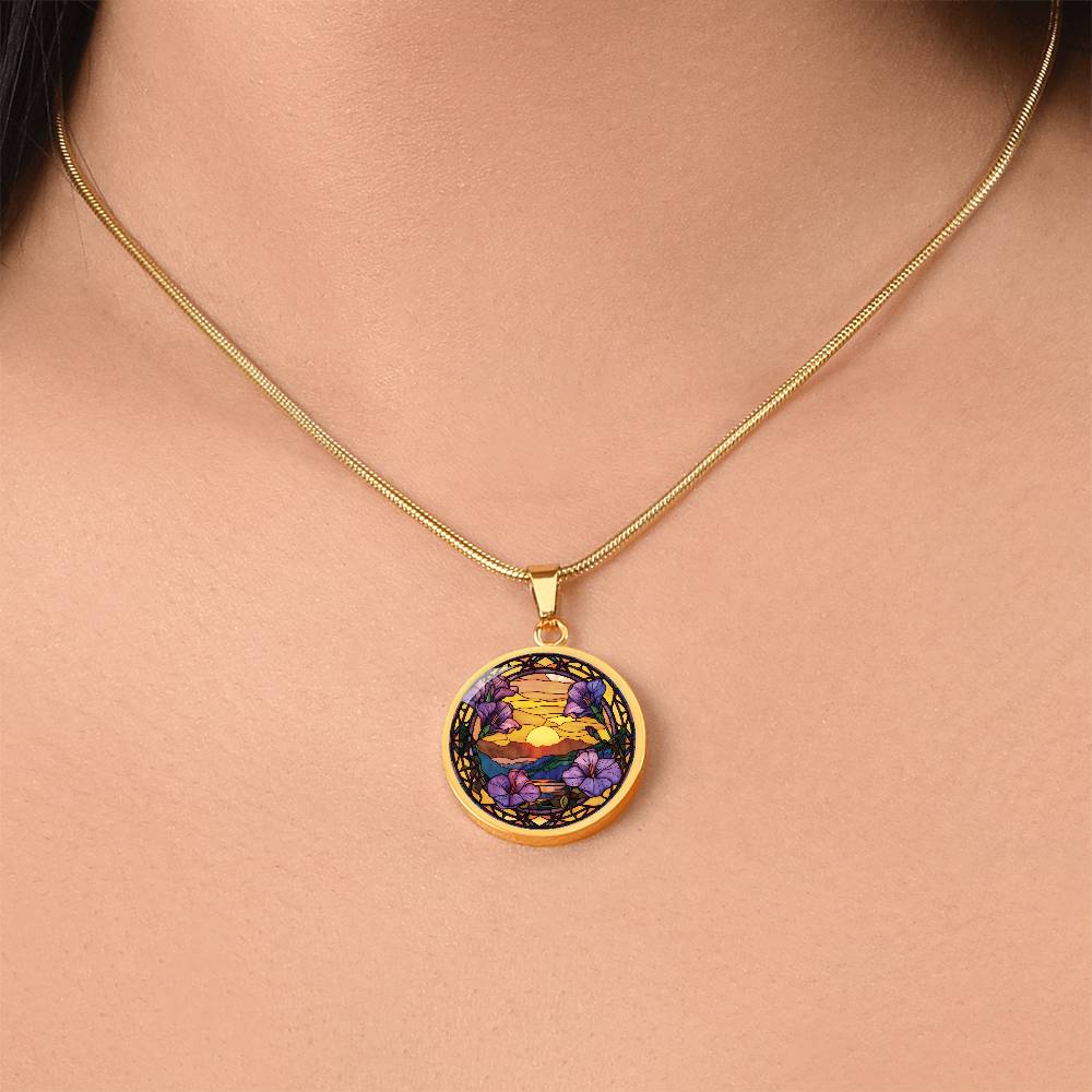 Woman wearing an elegant gold pendant Morning Glory Necklace. The colors are purple flowers, blue/green/purple hills, Brown mountains, Yellow sun and sky. This jewelry offers personalization with an engraving option for a name.