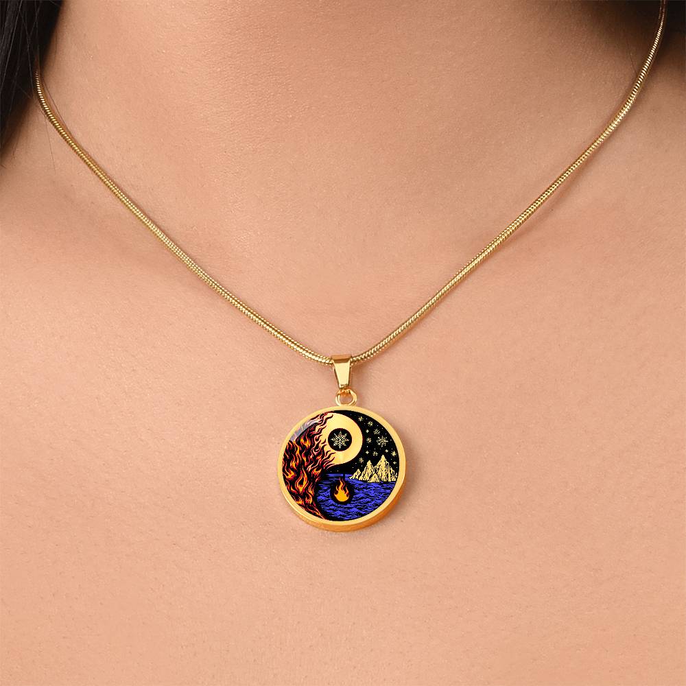 Woman wearing an Elegant gold pendant featuring a vivid Red/Orange Fire, Blue Water, gold snow flakes and gold Icebergs. set against a gold & Black backdrop. This jewelry offers personalization with an engraving option for a name.