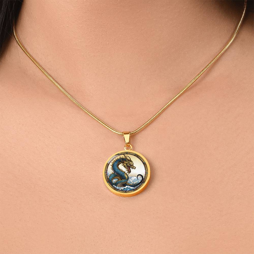 Woman wearing An Elegant gold pendant featuring a Water Dragon Necklace. Blue and yellow Dragon with a blue ocean, tan border and backdrop. This jewelry offers personalization with an engraving option for a name.