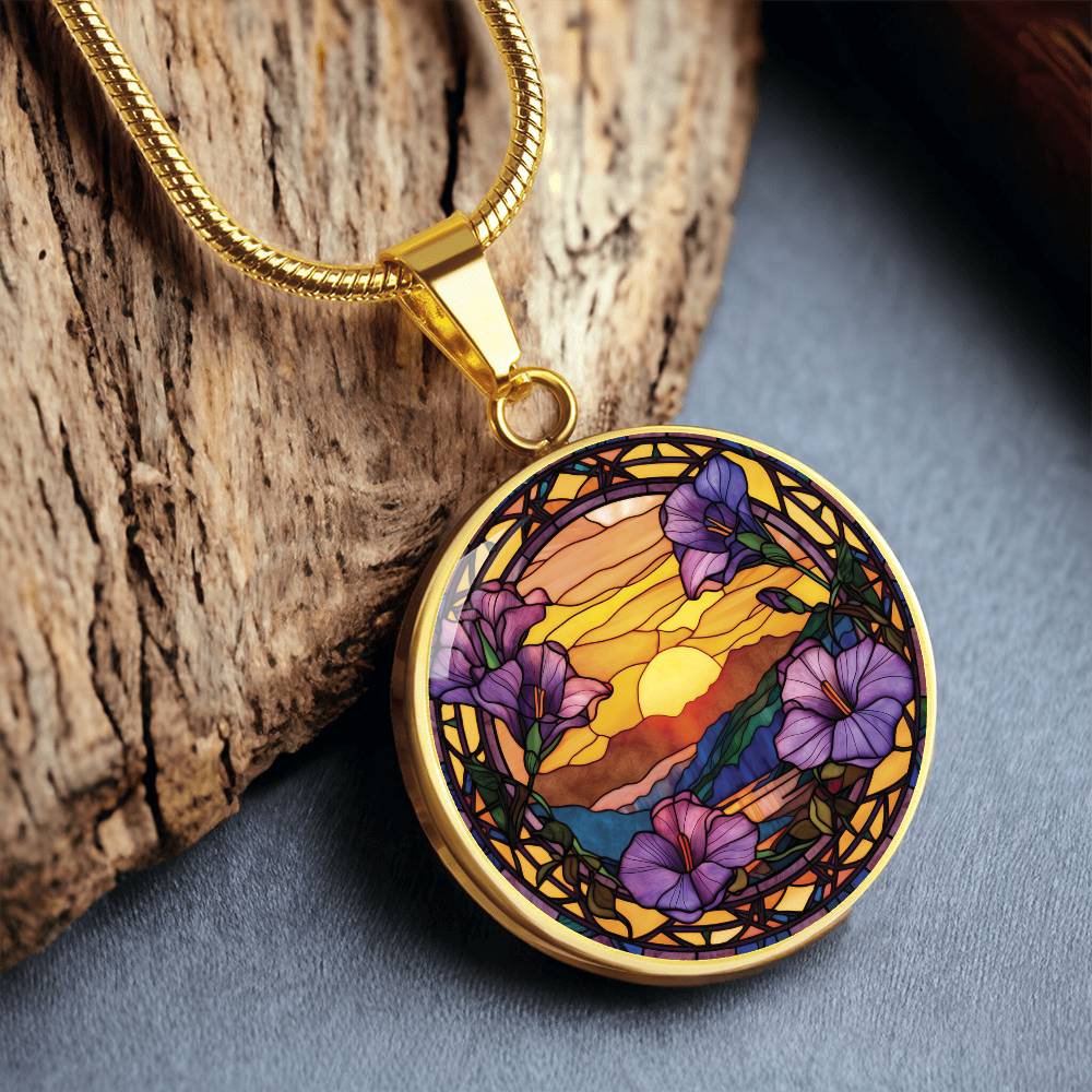 an elegant gold pendant Morning Glory Necklace. The colors are purple flowers, blue/green/purple hills, Brown mountains, Yellow sun and sky. This jewelry offers personalization with an engraving option for a name.