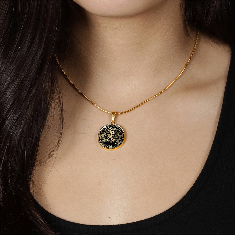 Woman wearing a Year of the dragon necklace. Elegant gold pendant with a rabbit & dragon, is set against a gold backdrop. This jewelry offers personalization with an engraving option for a name.