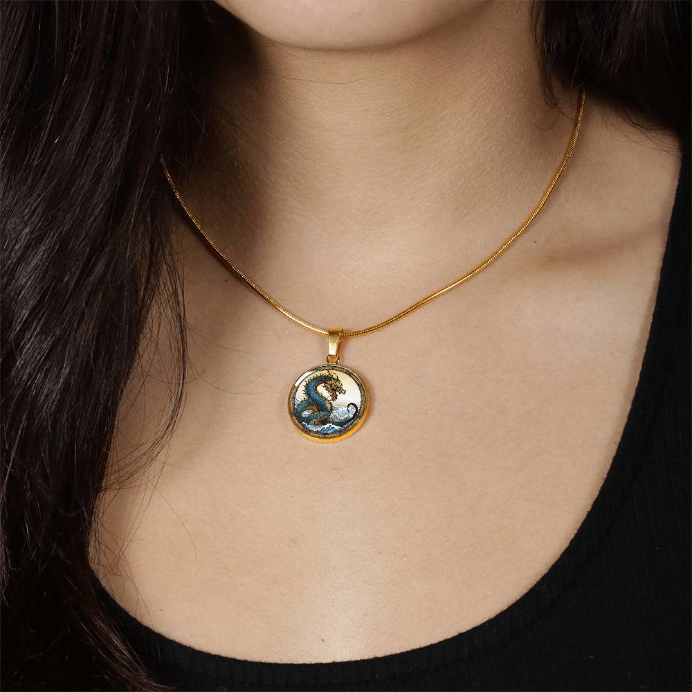 Woman wearing An Elegant gold pendant featuring a Water Dragon Necklace. Blue and yellow Dragon with a blue ocean, tan border and backdrop. This jewelry offers personalization with an engraving option for a name.