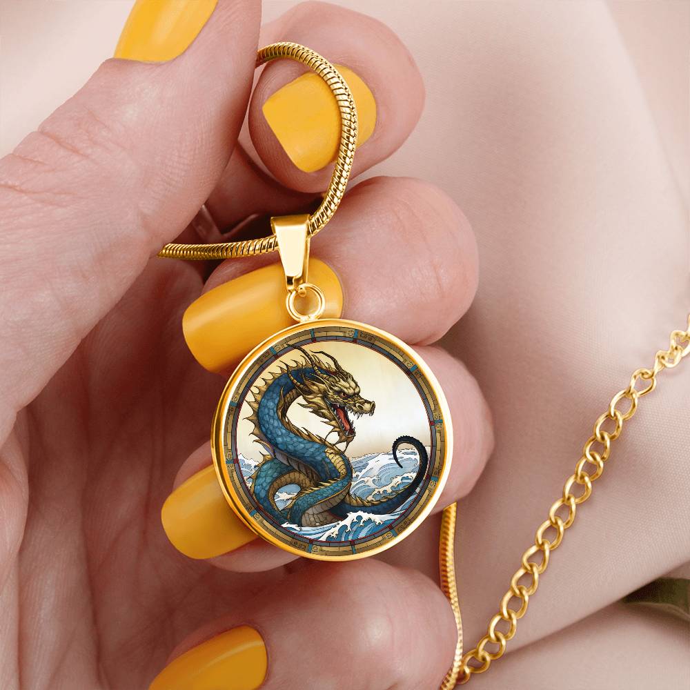 Woman holding An Elegant gold pendant featuring a Water Dragon Necklace. Blue and yellow Dragon with a blue ocean, tan border and backdrop. This jewelry offers personalization with an engraving option for a name.