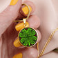 Woman holding an Elegant gold pendant necklace featuring a vivid Celtic four leaf clover with four red & Green hearts, set against a subtle Black & gold backdrop. This jewelry offers personalization with an engraving option for a name.