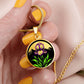 Woman holding a Februarys birth month flower Elegant gold pendant featuring a vivid Purple Iris Necklace set against a Green Grass, Gold sun and mountains background. This necklace offers personalization option for a name.