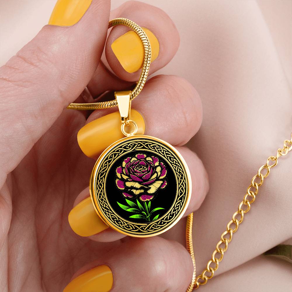 Woman holding an Elegant January gold pendant Celtic Carnation Birth Flower necklace featuring a vivid pink, green and gold flower, set against a black backdrop. This jewelry offers personalization with an engraving option for a name.