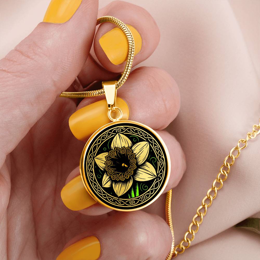 Woman holding an Elegant gold pendant featuring a vivid Yellow Daffodil Birth Flower Necklace, March birth month flower, set against a Green & Black backdrop with a Celtic border. Personalization with an engraving option for a name.