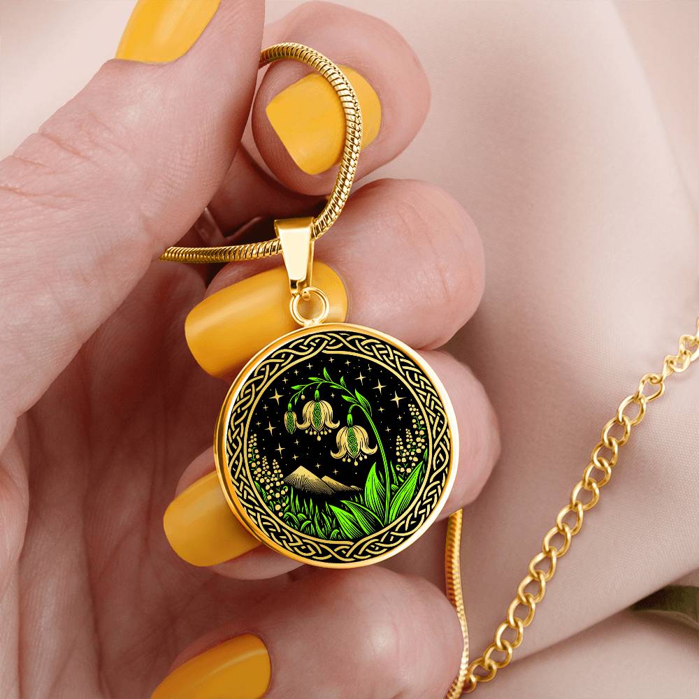 Woman holding An Elegant gold pendant Celtic Lily Of The Valley Necklace featuring Green Grass, gold Mountains, Stars,  Lily Of The Valleys, Celtic Knot Frame with a black backdrop. This jewelry offers personalized engraving option for a name.