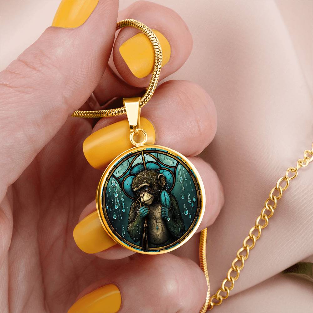 Woman holding an elegant gold pendant Chinese Zodiac Monkey Necklace. The colors are yellow, blue, teal, brown and green. This jewelry offers personalization with an engraving option for a name.