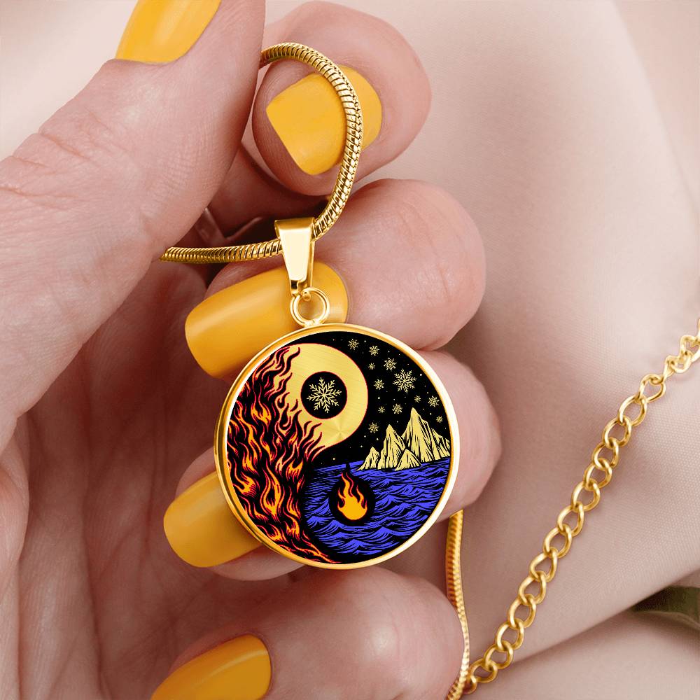 Woman holding an Elegant gold pendant featuring a vivid Red/Orange Fire, Blue Water, gold snow flakes and gold Icebergs. set against a gold & Black backdrop. This jewelry offers personalization with an engraving option for a name.