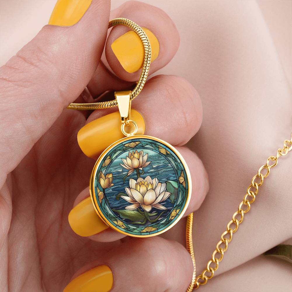 Woman holding an elegant gold pendant Water Lily Necklace. The colors are Green Leaves, Blue Water and Tan Flowers. This jewelry offers personalization with an engraving option for a name.