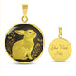 An Elegant gold pendant Rabbit Necklace. Yellow Rabbit and Flowers with a black and brown backdrop. This jewelry offers personalization with an engraving option for a name.